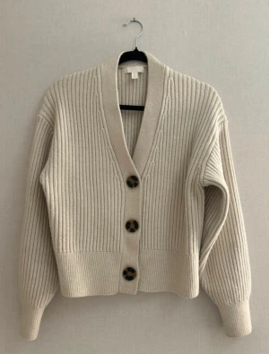 Beige ribbad v-ringad kofta - Säljer en jättefin beige ribbad v-ringad stickad kofta från H&M i storlek XS. Koftan har 3 bruna fina stora knappar längst fram! Säljer den då den tyvärr inte kommer till användning någon mera. Har inga fläckar eller liknande och är i mycket bra skick! Pris kan självklart diskuteras! Djur och rökfritt hem! ❤️  Varumärke: H&M Storlek: XS Skick: Mycket bra Färg: beige