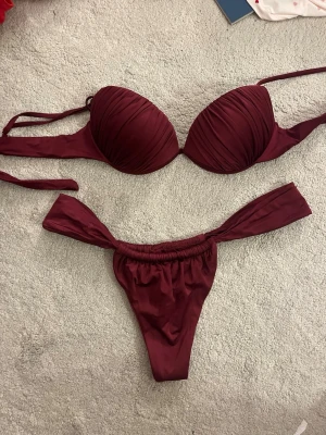 Vinröd bikini från Calzedonia - Snygg vinröd bikini från Calzedonia med vadderad överdel och knyt i sidorna både upptill och nedtill. Bikinin har en stilren design och är perfekt för stranden eller poolen. Materialet känns mjukt och följsamt mot huden.
