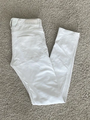Replay Jeans - Säljer ett par vita slim jeans från Replay med klassisk femficksdesign. Jeansen har smal passform och är tillverkade i ett stretchigt material för extra komfort. Perfekta för dig som vill ha en clean och fräsch look. Skriv om du har frågor!