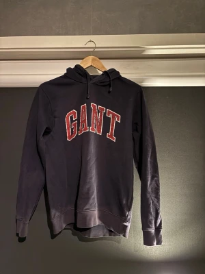 Gant hoodie  - Säljer denna snygga gant hoodie! Marin blå med röda detaljer |denna är ganska använd men texten har lossnat i tvätten men den har mycket kvar att ge!| Den är storlek M men sitter mer som S| Nypris ligger runt 1000kr skick 8/10| hör av dig vid intresse, ciao!