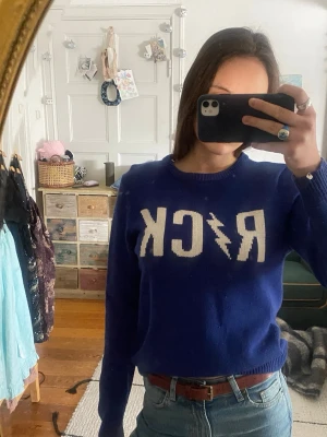 Zadig Voltaire Blå stickad tröja med ROCK-tryck - Cool blå stickad tröja med vit text 'ROCK' och blixt på bröstet. Rund halsringning och långa ärmar. Perfekt för dig som gillar att sticka ut och vill ha en unik look. Passar till jeans och sneakers.