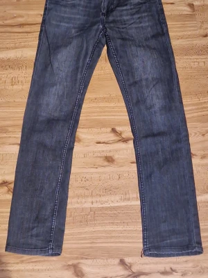 Svarta slim fit jeans från Levi's - Snygga mörkblå jeans från Levi's med slim tapered passform och femficksmodell. Jeansen har kontrastsömmar och subtila slitningar framtill för en avslappnad look. Tillverkade i slitstark denim med Levi's ikoniska bakfickor och röd etikett.