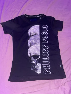 💀Philipp Plein t-shirt💀 - Cool svart t-shirt från Philipp Plein med ett stort glittrigt döskalletryck och logotyp i gotisk stil längs framsidan. T-shirten har rund hals och korta ärmar, perfekt för dig som gillar edgy och trendiga plagg. Pris kan diskuteras vid snabb affär🤩