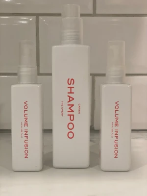 The Every schampo & volymspray set - Snyggt set från The Every med en vit flaska schampo och två matchande volymsprayer, alla i stilren fyrkantig design med röd text. Perfekt för dig som vill boosta volymen i håret och samtidigt ha snygga produkter i badrummet.