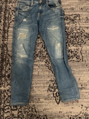 Ljusblå slitna jeans med raka ben - Säljer ett par ljusblå jeans reddish washed look och slitningar framtill. Jeansen har raka ben, klassisk femficksmodell och detaljerade sömmar på bakfickorna. Perfekta för en avslappnad streetstil.