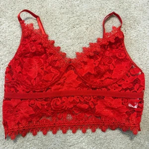 Röd spetsbralette från SHEIN - Snygg röd bralette från SHEIN i spets med blommigt mönster och tunna axelband. Braletten har dekorativ kant nertill och är tillverkad i polyester och elastan för en bekväm passform. Perfekt för dig som gillar feminina detaljer och trendig stil.