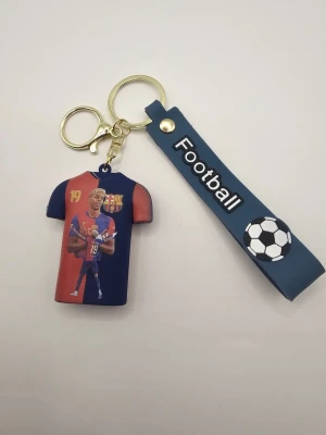 Nyckelring med fotbollstema och tröja - Cool nyckelring med blått band där det står 'Football' och en liten fotboll. Tröjan är röd och blå med nummer 19 och texten 'Lamine Yamal', inspirerad av FC Barcelona. Perfekt accessoar för fotbollsfans.
