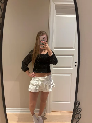 Svart blus - Trendig svart blus med vita stjärn- och konstellationsmönster. Smockad kropp och långa, transparenta ärmar ger en snygg och bekväm passform. Perfekt till jeans eller kjol för en cool look. Lite för liten för mig därför ja säljer då den ä lite för kort för mig! 