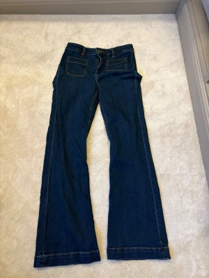 Mörkblå bootcut jeans med fickor - Snygga mörkblå jeans med bootcut passform och två stora fickor fram och bak. Strl M