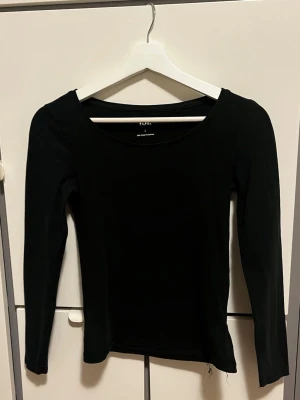 Svart långärmad topp från 157 - En stilren svart långärmad topp från 157 med rundad halsringning. Toppen är i mjukt bomullsmaterial och har en luftig passform. Stilren tröja som går att matcha med allt