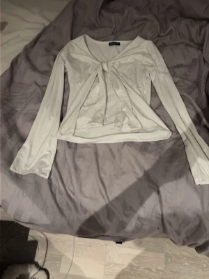 Vit långärmad topp med knyt - Snygg vit långärmad topp med v-ringning och knyt framtill. Är från Missäy står inte storlek men skulle gissa på XS och knappt använd.