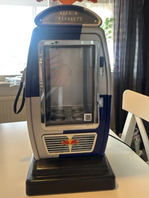 Red Bull minikyl i retrostil - Cool minikyl från Red Bull i retro bensinpumpsdesign. Färgerna är blå, silver och svart med Red Bull-logga på både fram- och baksida. Kylen har glasdörr och plats för flera burkar, perfekt för energidryck. Elanslutning på baksidan.