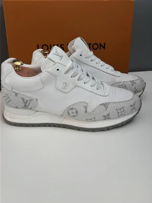 Vita Louis Vuitton sneakers med monogram - Louis Vuitton sneakers i vitt läder och textil med klassiskt LV-monogram i grått på sidorna och fram. Lågt skaft, vita snören och robust grå sula med LV-logga undertill. Perfekt för dig som vill ha exklusiva och stilrena sneakers. Frågor kom privat jag tar även Prisförslag!