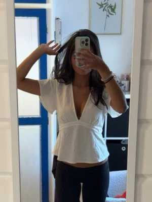 Vit omlottop med knytband - Snygg vit omlottopp med v-ringning och korta ärmar. Använd endast 1 gång så superfint skick!!!!Från Gina Tricot 😍