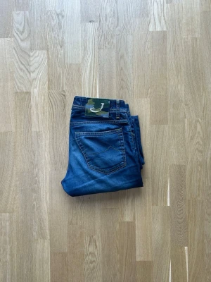 Blå jeans från Jacob Cohen - Säljer ett par klassiska blå jeans från Jacob. Jeansen har normal midja, raka ben och ett coolt patch med logga bak i midjan. Perfekta för en avslappnad och trendig stil.