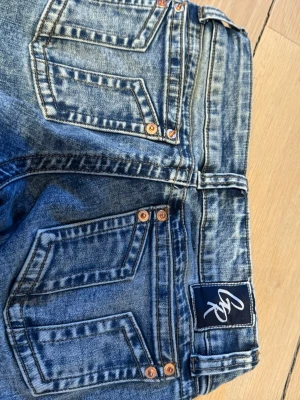 Blå raka jeans från GRise - Snygga blå jeans från GRise med raka ben och klassisk femficksdesign. Jeansen har en tvättad look med tydliga sömmar och kopparfärgade nitar. Märkespatch bak i midjan. Perfekta för en avslappnad och trendig stil.