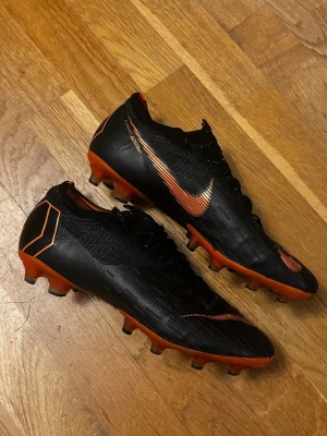 Nike Mercurial Vapor fotbollsskor - Säljer ett par svarta och orange Nike Mercurial Vapor i storlek 42. Inga synliga eller större skador på skorna så mycket bra skick på de! Skriv för frågor!