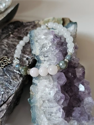 Armband med halvädelstenar som Rosenkvarts larvikit, Labradorit och bergskristall  - Snyggt armband med halvädelstenar som Rosenkvarts, Bergskristall, larvikit och Labradorit,, dekorerat med små silvriga glittriga detaljer. Armbandet har en stretchig design och en liten metallberlock. Perfekt accessoar för att lyfta din stil. Armbandet kommer i en söt liten påse tillsammans med information om kristallernas magiska egenskaper. 