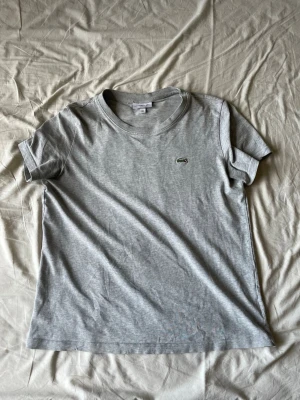 Lacoste t-shirt - Helt vanlig grå Lacoste t-shirt i storlek S. Passar till det mesta. Skick 8/10 inga tydliga defekter. Skirv gärna om ni har frågor