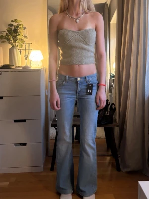 Stickad topp från Zara! - Supersnygg ljusgrå tubtopp med ribbad struktur och croppad passform. Toppen är axelbandslös och sitter tight mot kroppen, perfekt för varma dagar eller lager på lager. Enkel att matcha med både jeans och kjol.