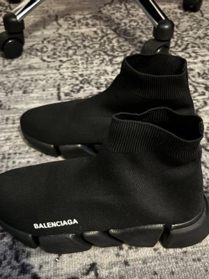 Svarta Speed sneakers - Säljer ett par svarta Speed sneakers med strumpliknande ovandel och chunky sula. Skorna har vit logga på sidan och är tillverkade i stretchigt syntetmaterial för en modern och sportig look.