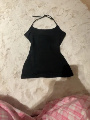 Svart halterneck linnetopp H&M XS - Säljer en svart halterneck linnetopp från H&M i storlek XS. Toppen har smala band som knyts i nacken och är figurnära med en enkel, stilren look. Perfekt att matcha med jeans eller kjol för en clean vibe.