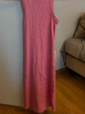 Rosa ribbad långklänning - Snygg rosa långklänning med ribbad struktur och ärmlös design. Klänningen har en rak passform och är perfekt för varma dagar. Enkel och stilren modell som är lätt att matcha med accessoarer.