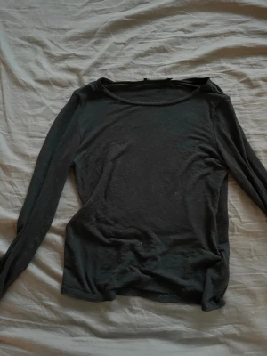 Svart långärmad topp från 157 - En enkel och stilren svart långärmad topp från 157 med rund halsringning. Perfekt att matcha med jeans eller kjol för en clean look. Tunn och mjuk i materialet, passar bra till lager-på-lager-stil. See through.