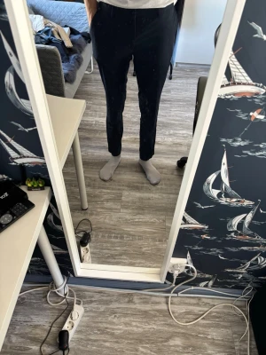 Mörkblå kostymbyxor med avsmalnande ben - Snygga mörkblå kostymbyxor med avsmalnande passform och klassisk midja. Byxorna har diskreta sidfickor och är perfekta för en stilren look. Materialet är en mjuk och lätt tygblandning. Passar dig som gillar en modern och enkel stil. Jag är 193cm lång och de är lite för små för mig, skulle säga att de passar för de som är under 190cm.