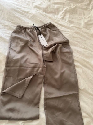 Satin byxor - Helt oanvända satinbyxor från Gina i färgen taupe! 
