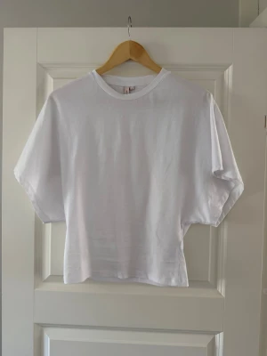 Vit basic t-shirt från Nelly - En klassisk vit t-shirt med rund hals och korta ärmar. Modellen är rak och något loose fit, perfekt till jeans eller shorts. Tillverkad i mjuk bomull för en skön känsla hela dagen.