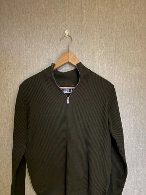 Svart stickad tröja med dragkedja - Snygg svart stickad tröja från Jack & Jones med halv dragkedja och ståkrage. Tröjan har ribbad struktur och är perfekt för lager-på-lager. Enkel och stilren design som passar till det mesta. Har aldrig använt den men tog väck den lappen 