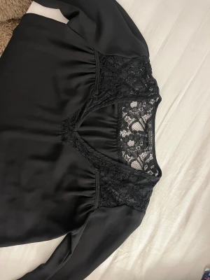 Svart blus med spetsdetaljer V-ringning - Stilren svart blus från H&M med fin spets vid V-ringningen. 