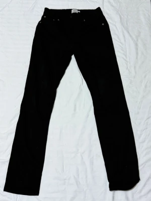 Svarta slim jeans från 157 - Säljer ett par svarta slim fit jeans från 157. Jeansen har klassisk femficksdesign och raka ben. Perfekta för dig som gillar en enkel och stilren look. Materialet känns mjukt och följsamt, vilket gör dem sköna att bära hela dagen.