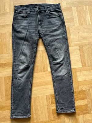 Nudie Jeans Lean Dean  - Tjena! Säljer ett par grå/svarta slim fit jeans från Nudie Jeans med en snyggt tvättad look och klassiska fem fickor. Modellen är Lean Dean och storleken är 32 30. Jeansen är sparsamt använda så inga skador eller slitningar. Priset är 499 men inte hugget i sten. Hör av dig vid minsta lilla fundering! 