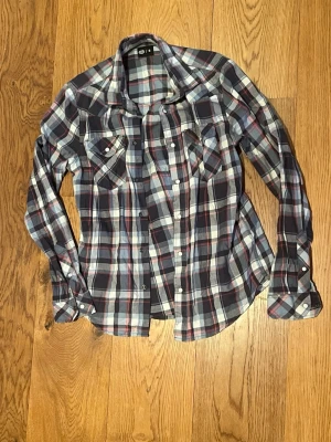 Vintage flanellskjorta från Crocker - Säljer den här galet snygga och sällsynta vintage flanellskjorta ifrån Crocker i storlek S. Skjortan har sjukt snyggt rutade mönster i rött, vitt och svart primärt. Väldigt skön och snygg passform. Skjortan har tryckknappar istället för vanliga vilket gör den betydligt smidigare att sätta på och ta av. Mycket bra skick inga defekter. Skriv vid eventuella funderingar✌️
