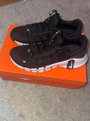 Svarta Nike Metcon 5 träningsskor - Snygga och sköna Nike Metcon träningsskor perfekta till träningen eller till casual outfits. Använda max 2 gånger så de är i MYCKET bra skick. Passar även 43 i storleken.