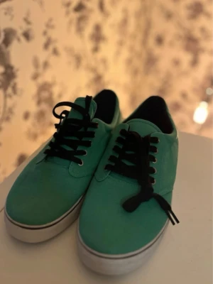 Gröna låga sneakers med svarta snören - Helt oanvända herrskor med svart sula och svarta skosnören. Klassisk låg modell med vit kant runt sulan och svart insida. 