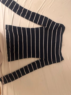 Marinblå stickad tröja från Amisu - Säljer en marinblå stickad tröja från Amisu med vita horisontella ränder. Tröjan har lång ärm, ribbstickad struktur och en klassisk, smal passform. Perfekt för dig som gillar stilrena och tidlösa plagg. ( den har 2 hål vid ärmen ) 