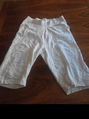 Vita capri leggings - Säljer ett par vita capri leggings med resår i midjan. De är tillverkade i ett mjukt och stretchigt material som sitter skönt mot kroppen. Perfekta till sommaren och lätta att matcha med olika toppar.