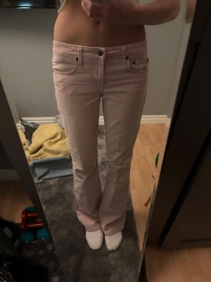 Ljusrosa bootcut jeans - Säljer ett par ljusrosa jeans med bootcut passform. Jeansen har normal midja och stängs med knapp och dragkedja. Jag är 169 cm och dom passar mig i längden. Använda ett få tal gånger. 