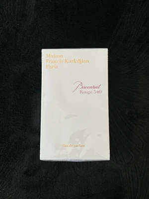 Baccarat Rouge 540 Eau de Parfum - Maison Francis Kurkdjian Baccarat Rouge 540 Eau de Parfum i elegant vit kartong med guld- och rödfärgad text. Lyxig och ikonisk doft från Paris, perfekt för dig som vill ha något exklusivt i parfymhyllan.