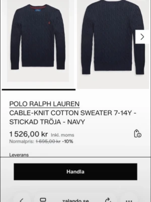 Mörkblå kabelstickad tröja Polo Ralph Lauren - Kabelstickad mörkblå tröja från Polo Ralph Lauren i 100% bomull. Klassisk rund halsringning, ribbade muddar och ikonisk röd logga broderad på bröstet. Perfekt för en stilren och avslappnad look.