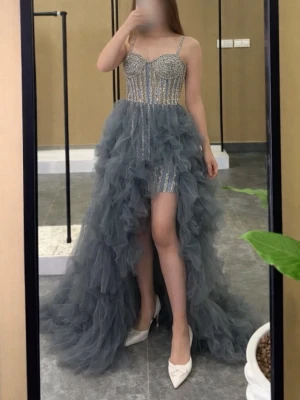 Glittrig blå långklänning med volang - Säljer en unik blå långklänning med glittrig överdel och tunna axelband. Kjolen har volanger i flera lager och är kort framtill och lång bak. Perfekt för dig som vill sticka ut på bal eller fest! Materialet är troligtvis polyester och satin.( Har haft den en gång)