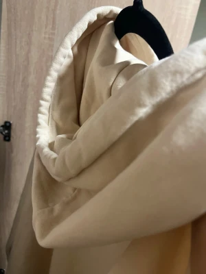 Beige hoodie New York City 83 H&M - Snygg beige hoodie med huva och känguruficka framtill. Tryck med texten 'New York City' och siffran 83 i rött och svart på bröstet. Mjuk bomullskänsla och ribbade muddar vid ärmslut och nederkant. Perfekt för en avslappnad streetwear-look. Använd 2 gånger helt ny 