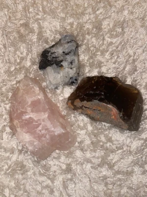 Stenkit med tre olika mineraler - Säljer ett kit med tre råa mineralstenar: en ljusrosa sten (rosenkvarts), en svartvit sten och en mörkbrun sten (rökkvarts). Perfekt för dig som gillar kristaller, dekoration eller samling. Stenarna har naturliga former och varierande storlek.