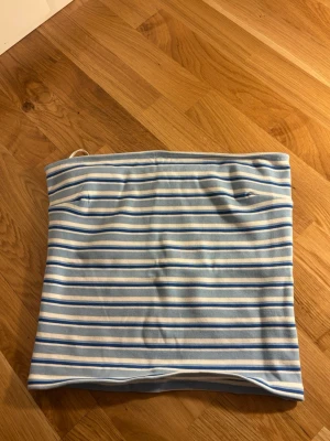 Bandå topp - Säljer en söt tubtopp med ljusblå och vita ränder. Toppen är axelbandslös och har en bandeauformad passform. Perfekt till sommaren och enkel att matcha med jeans eller kjol. Funkar även som kjol ❤️