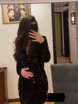 Svart glittrig kortklänning - Säljer en svart glittrig kortklänning med v-ringning och långa ärmar. Klänningen har en figurnära passform och är täckt av paljetter som ger ett riktigt snyggt partyvibe. Perfekt för dig som vill sticka ut på nästa event!