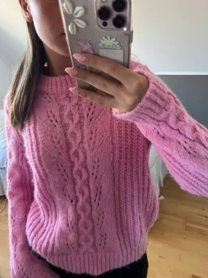 Rosa stickad tröja - Säljer en rosa stickad tröja med kabelstickat mönster och håldetaljer. Tröjan är supermjuk i materialet, perfekt till våren och sommaren!! Endast använd två gånger, så den är i fint skick😍🙌🏻