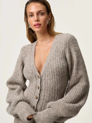 Adoore klänning  - Säljer en beige ribbad stickad långklänning med v-ringning och knappar framtill. Klänningen har långa, puffiga ärmar och är figurnära i modellen. Perfekt för dig som gillar en mysig men ändå stilren look.